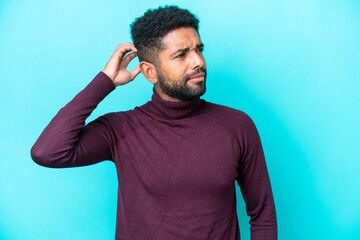 Young Brazilian man isolated on blue background having doubts while scratching head