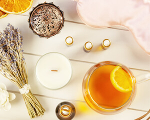 Relax at home. Cup of herbal tea, aroma candle, sticks, lavender flowers, dry oranges and natural oils on wooden background. Insomnia or depression treatment. Self care and me time concept