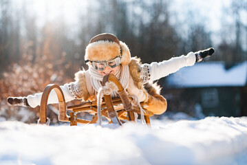 Funny little child runs on sledge in snow. Active sports games in winter time. Happy winter...
