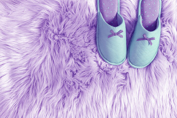 Green house slippers on purple fluffy carpet. Purple fluffy soft fur carpet as background. Flat lay, top view, copy space