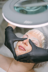 Cosmetologist and dermatologist makes a moisturizing, rejuvenating woman lying patient in a beauty salon.