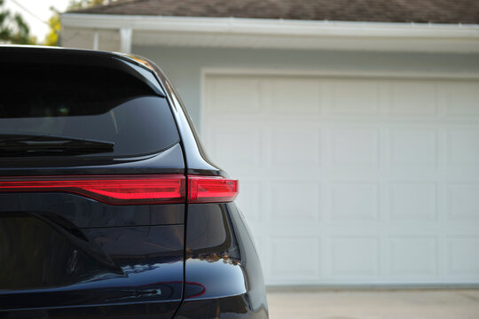 Car Parked In Front Of Wide Garage Double Door On Concrete Driveway Of New Modern American House