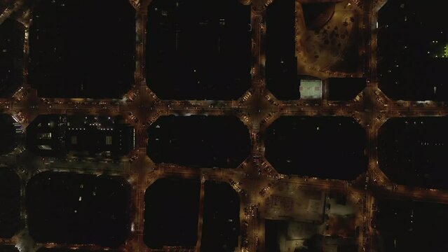 Overhead view of illuminated streets in city from height. Night traffic in urban borough. Barcelona, Spain
