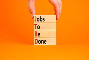 JTBD jobs to be done symbol. Concept words JTBD jobs to be done on wooden blocks on beautiful orange background. Businessman hand. Business and JTBD jobs to be done concept. Copy space.
