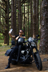 Fototapeta na wymiar Motero con moto custom haciéndose un selfie en el bosque