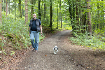 a man is walking with his dog on a forest path