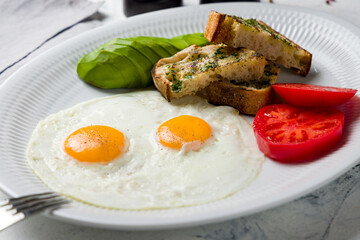 Fried eggs with tomatoes, avocado and fried croutons