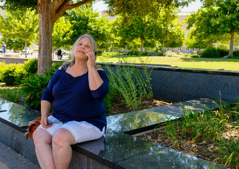 Elderly white woman sitting talking on her phone.