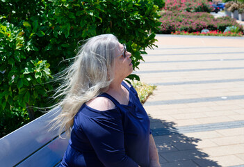 Elderly white woman sitting on park bench admiring the view