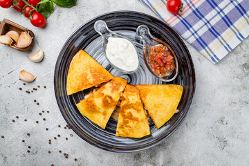 Mexican Quesadilla with chicken and sour cream and salsa sauce on plate top view