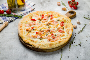 Pizza with salmon and anchovies with tomatoes on grey table