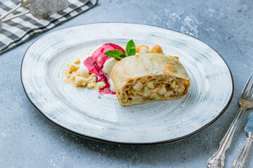 Apple strudel with ice cream on grey table