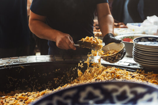 uzbek imposes the national dish "pilaf" in uzbekistan. preparation for dinner in a tourist place in tashkent. packing rice on plates in tashkent