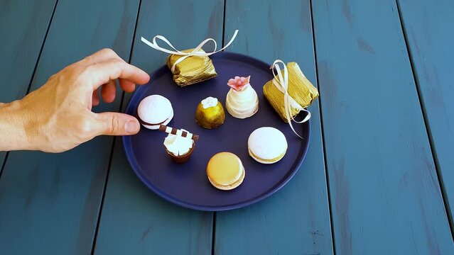 Man picking up a macaron, next to other fancy sweets from weddings_top view.