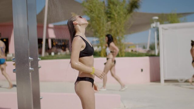 young beautiful sexy tanned woman in bikini taking summer shower on pool sea beach
