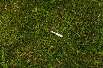 an unextinguished cigarette on the grass. fire hazard from a discarded cigarette.