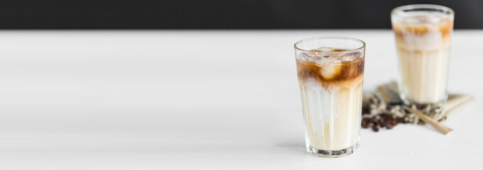 Banner Ice coffee in a glass with cream over and coffee beans on table with copy space