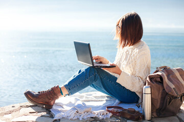 Freelancer workplace at sea beach. Young woman working in traveling from office at nature. Girl...