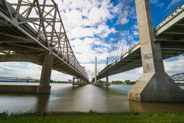 The Abraham Lincoln Bridge and John F. Kennedy Memorial Bridge crossing the Ohio River from Kentucky to Indiana. Long exposure sky and water movement. - obrazy, fototapety, plakaty
