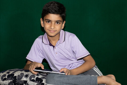 A boy sitting on counch with tablet computer