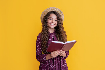 cheerful child with frizz hair read book on yellow background