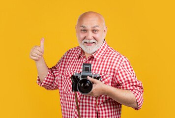 smiling aged man with retro photo camera on yellow baqckground