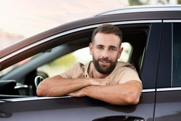 Portrait of handsome smiling latin driving sitting in car looking at camera. Transportation...