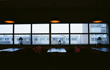 Empty cafe on a cold winter afternoon in Siauliai, Lithuania. Snowflakes flying behind the glass amidst socialist-era buildings