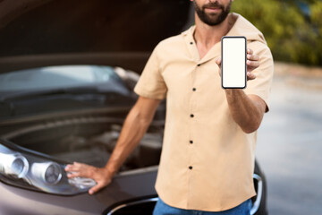 Man showing mobile phone screen with mockup standing near broken car, having engine problem on the...