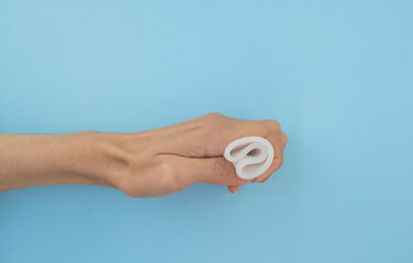Close-up of a woman's hand holding a menstrual cup against a blue background. Women's health concept, zero waste alternatives.