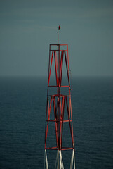 Telephone antenna. White and red antenna. Sea bottom. Blue sky


