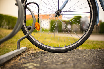 Detail of a front bicycle wheel locked to a bicycle stand.