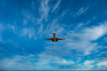 Airplane flying about to land. Airplane seen from below. Blue sky