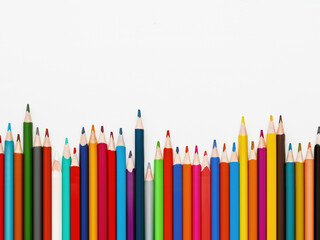 Row of colorful watercolor pencils. School supplies on light paper background. Top view on kid's stationery. Back to school. White background with copy space.