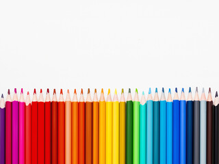 Vertical row of colorful pencils on white background. School supplies in colores of rainbow. Kid's stationery with copy space. Back to school backdrop.