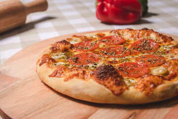 Detail view of personal pepperoni pizza on top of a table with a checkered tablecloth.