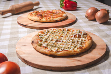 Personal pizzas of different flavors on a table with a checkered tablecloth.
