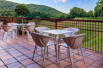 Table and chairs at an outdoor cafe with a view onto a green forest and meadow in Ultzama, Spain