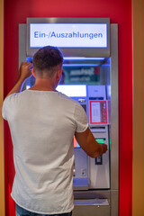 Mann hebt Geld am Bankautomaten ab