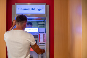 Mann hebt Geld am Bankautomaten ab