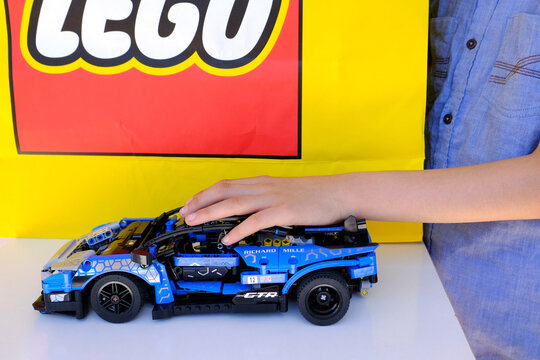 child, boy of 10 years old assembles blue car from Lego parts, educational constructor, concept development fine motor skills, training patience, logic, lego logo on background, Frankfurt - July 2022