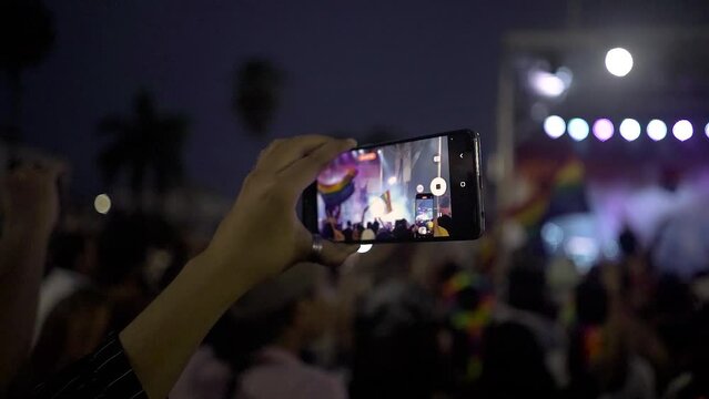 Celular filmando Show Banderas PRIDE colores LGBITIQ+ Nocturno publico