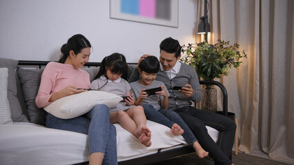 Fototapeta premium Family concept of 4k Resolution. Asian parents and children playing with mobile phones in the living room