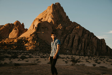 Naklejka premium traveler standing in the red rock desert of namibia