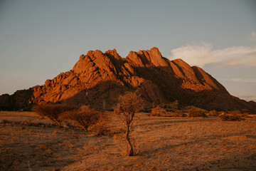 sun setting on red rock mountains in namibia desert