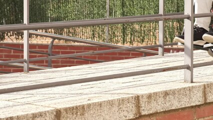 close-up of unrecognizable handicapped man in a wheelchair walking down a ramp in slow motion