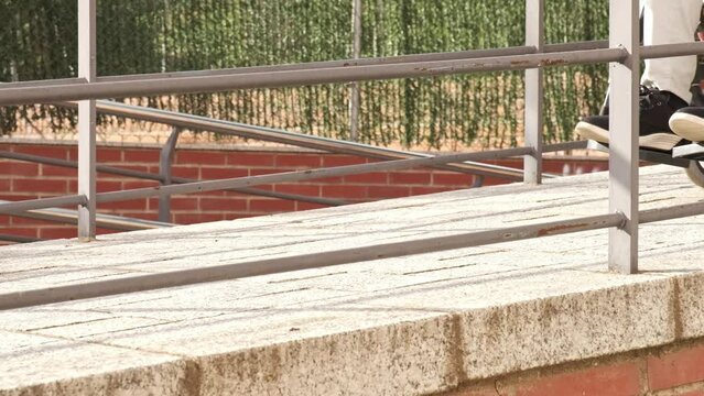 close-up of unrecognizable handicapped man in a wheelchair walking down a ramp in slow motion