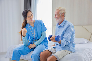 Hospice nurse is helping Caucasian man in bed to exercising muscle strength in pension retirement center for home care rehabilitation and post treatment recovery process