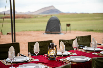 luxury dinner table set up in camp ground in desert of namibia with lantern