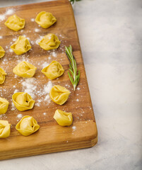 Appetizing raw homemade dumplings stuffed with minced meat on a cutting board sprinkled with flour on a white background. Delicious organic food, healthy lifestyle.